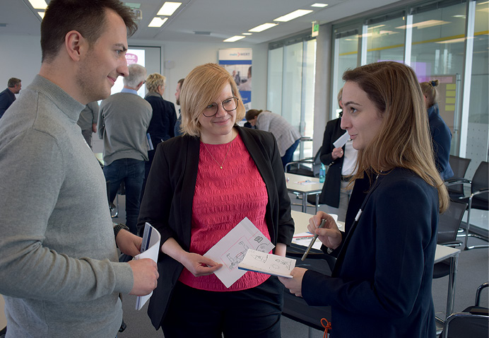 Drei Personen beim Aktionstag Berufliche Weiterbildung mit mehrWERT im Gespräch.