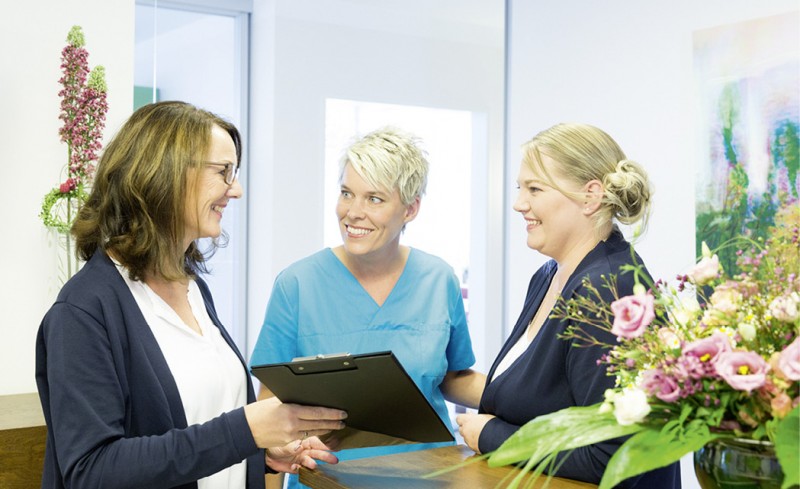 Zahnärztin Dr. Viktoria Saager im Gespräch mit zwei Mitarbeiterinnen