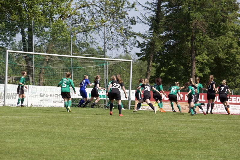 Zwei Damenfußballmannschaften in Aktion vor einem Tor.