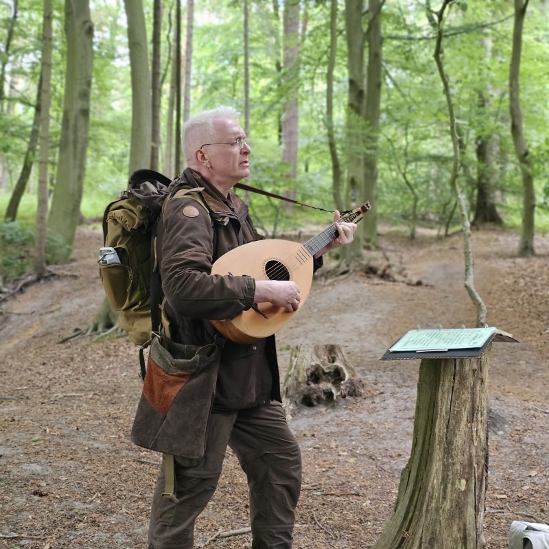 Ein Mann, der im Wald Gitarre spielt
