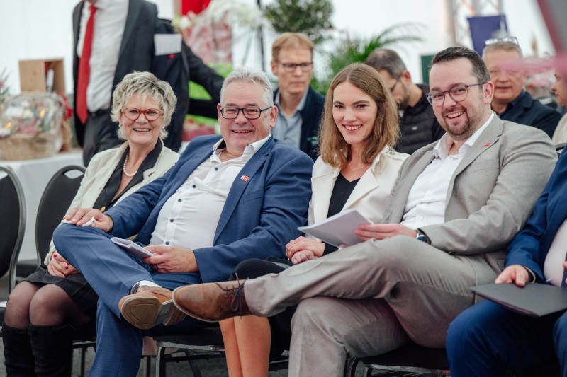 Menschen sitzen in einer Reihe und lächeln in die Kamera