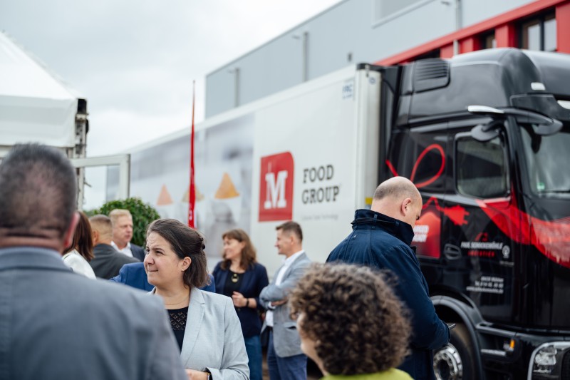 Menschen vor LKW mit Logo