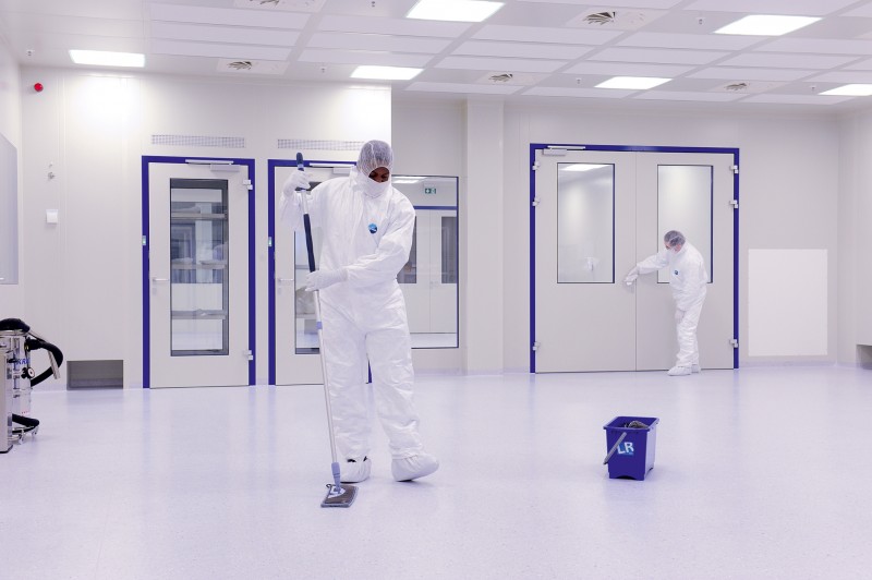 Zwei Mitarbeiter in Arbeitsschutzkleidung bei der Reinraumreinigung