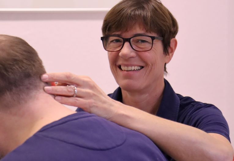 Eine Ärztin mit ihrer Hand im Nacken eines Patienten