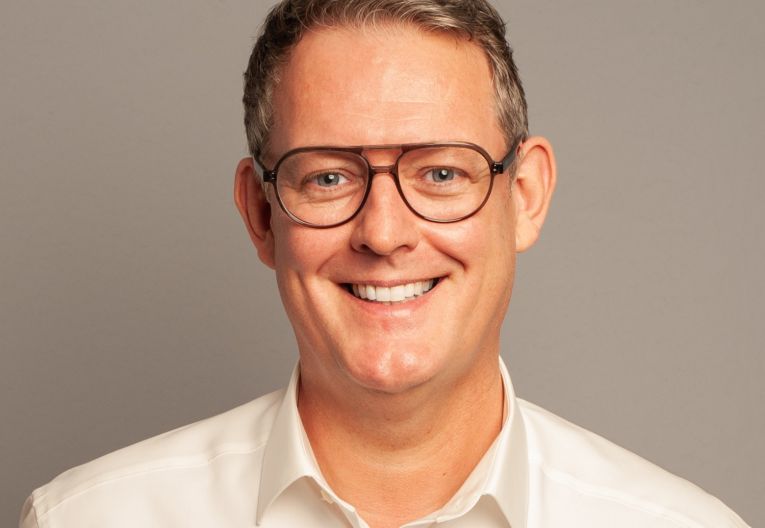 Mann mit Brille lächelt in die Kamera