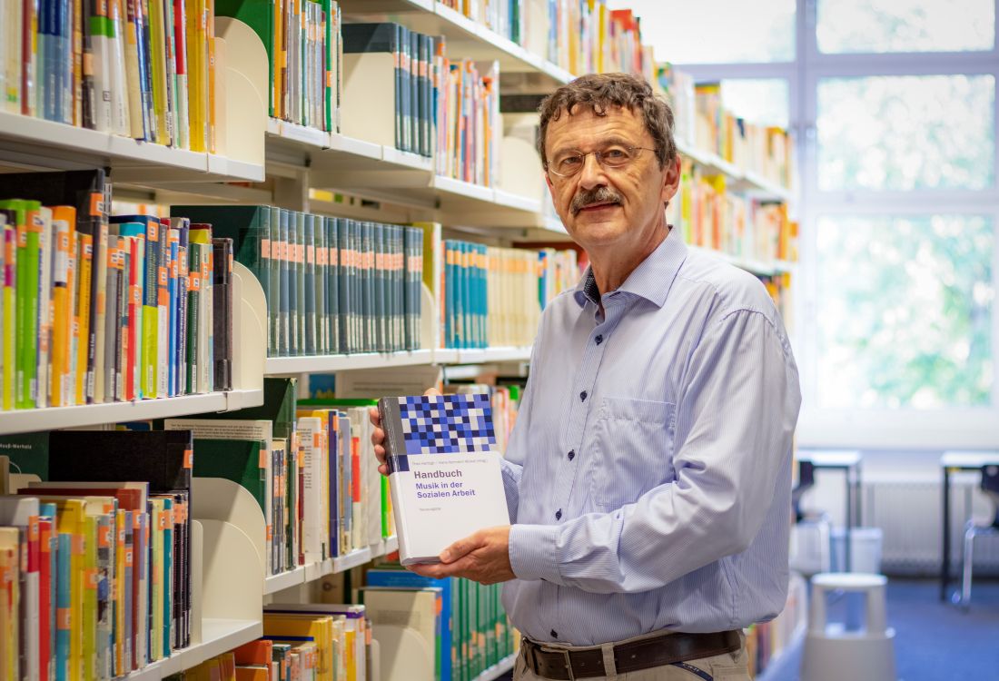 Mann mit Buch in der Hand vor Regal